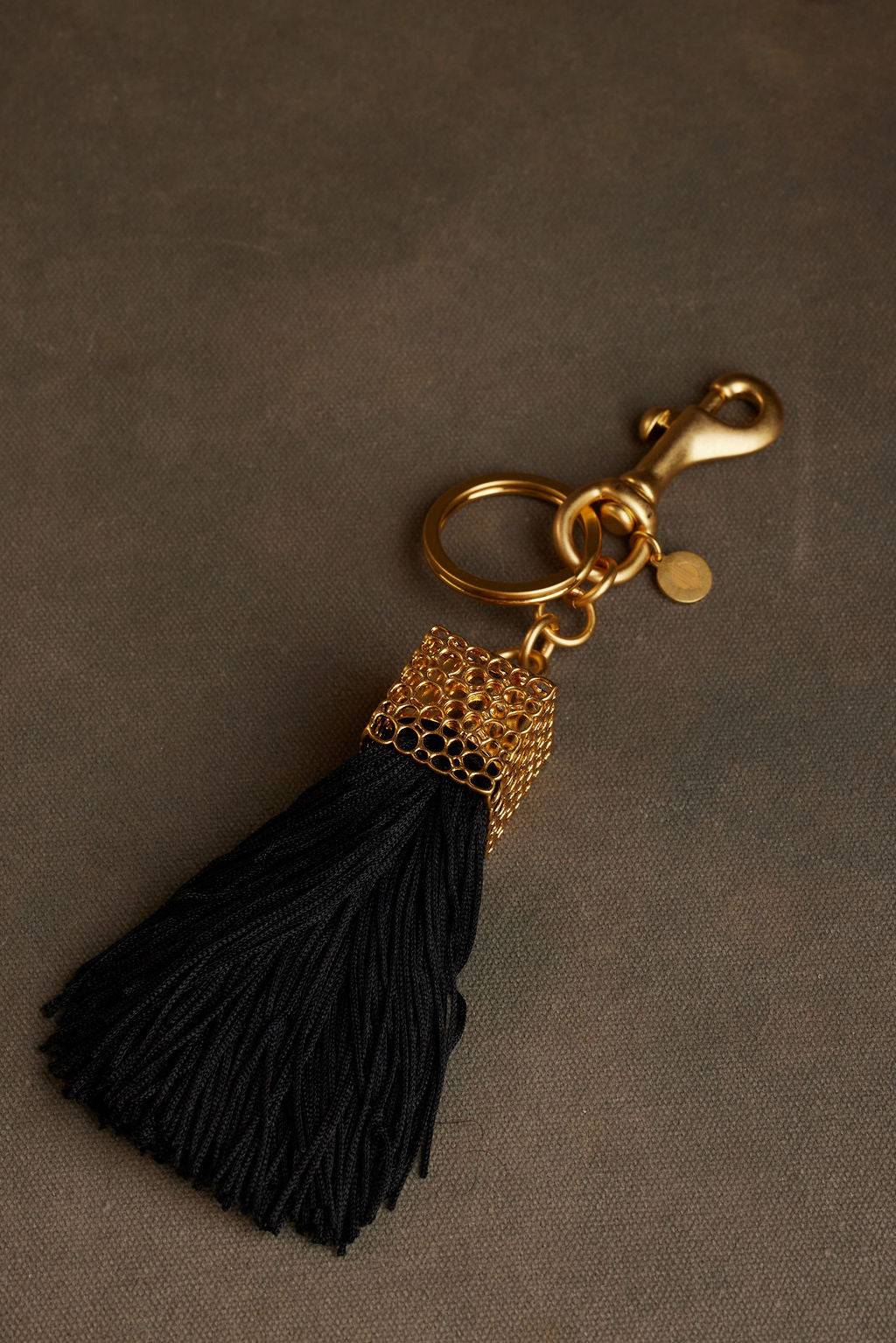 Black tassel keychain with gold accents on a brown background