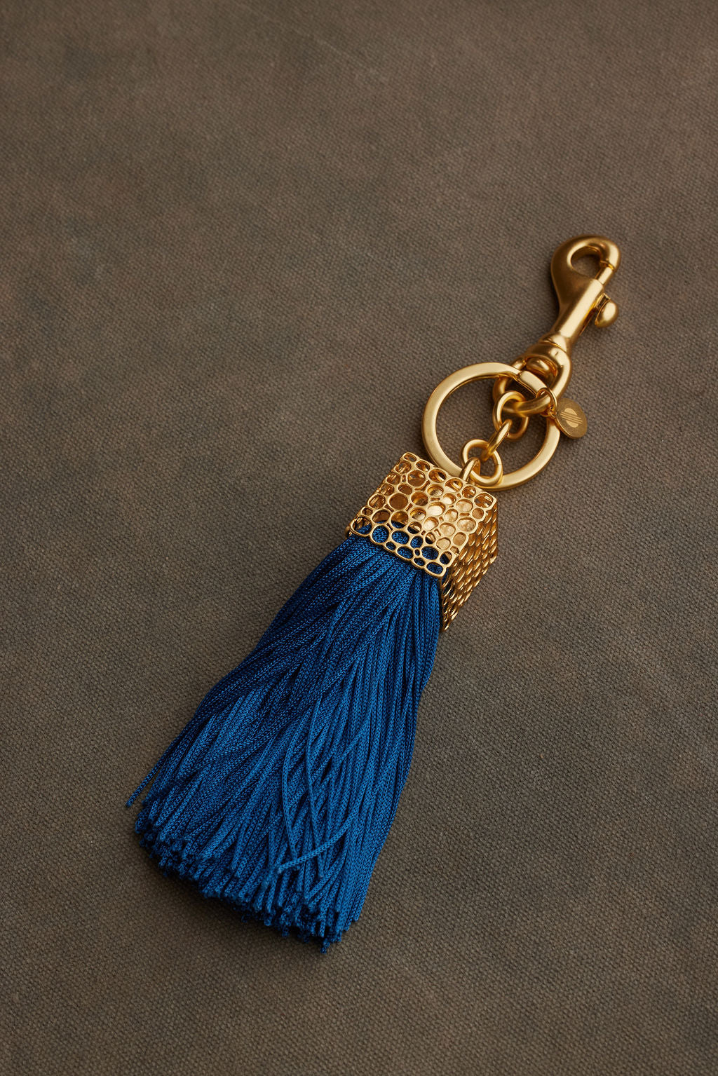 Blue tassel keychain with gold clasp on a brown background