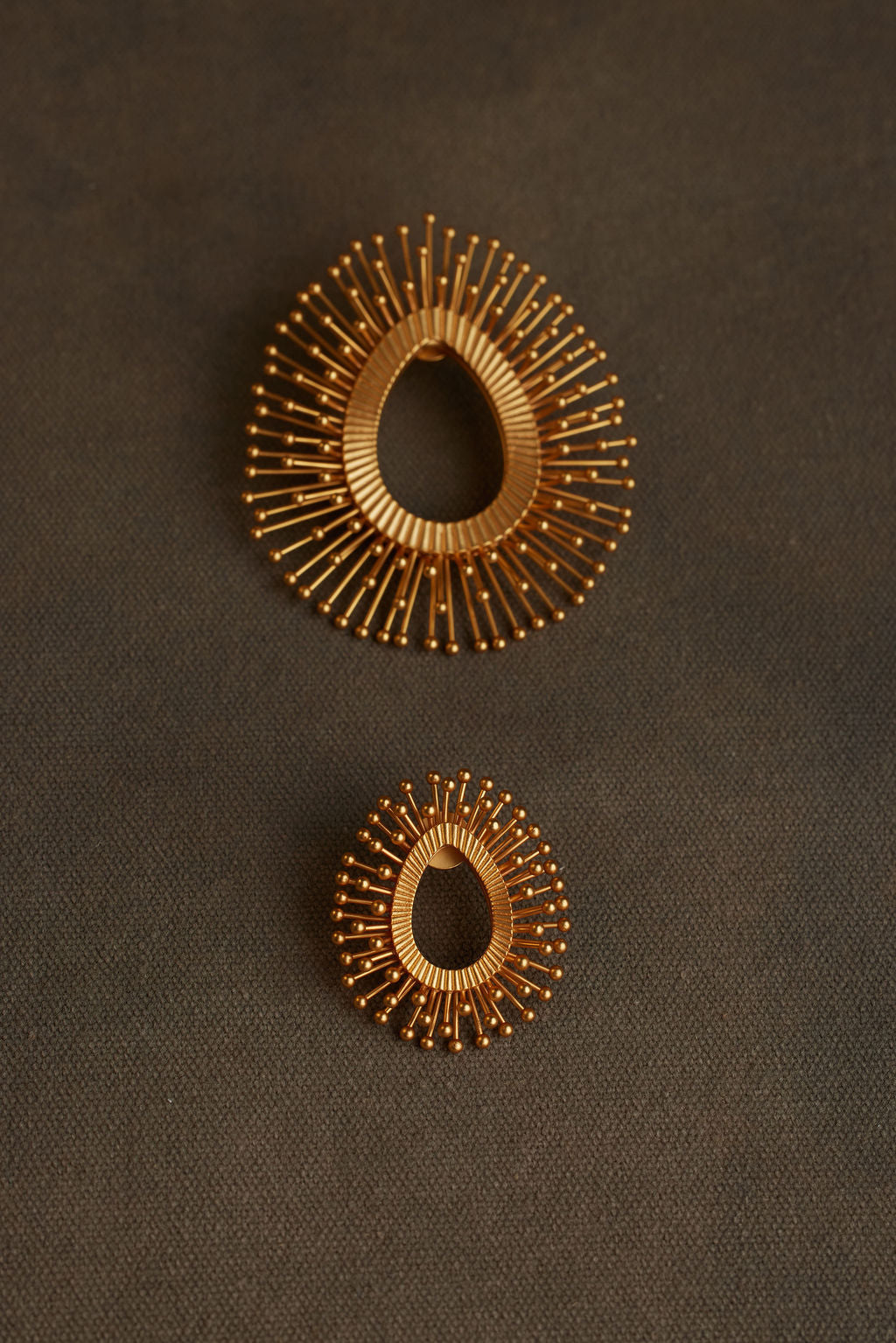Pair of gold hoop earrings on a dark fabric background