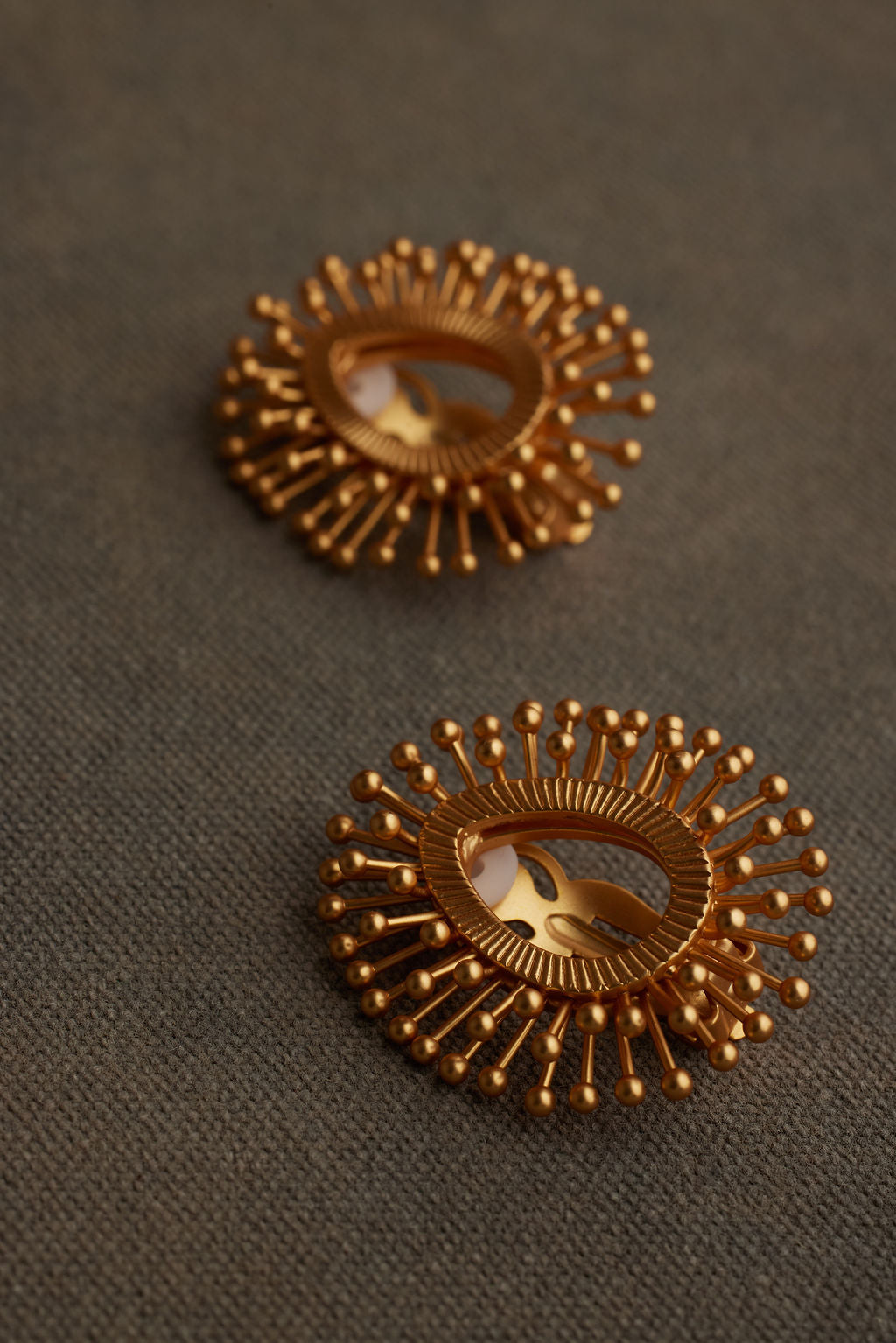 Pair of gold earrings on a textured brown surface
