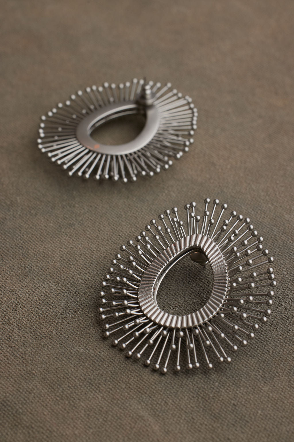 Pair of silver hoop earrings on a brown surface