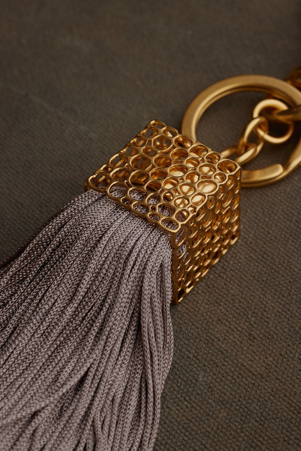 Gold keychain with a tassel on a dark background