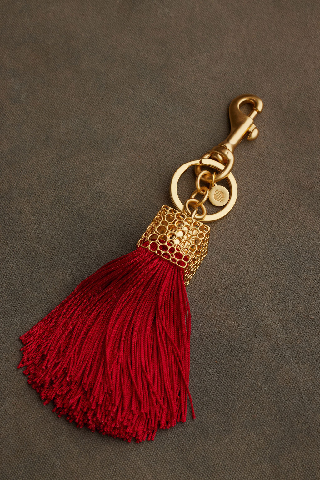 Red tassel keychain with gold clasp on a gray background