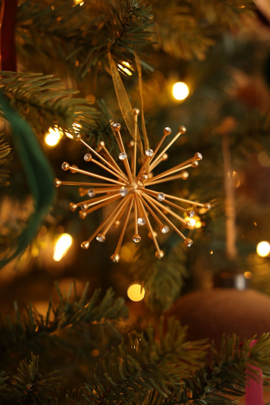 CRYSTAL star-shaped ornament on a Christmas tree with blurred lights in the background