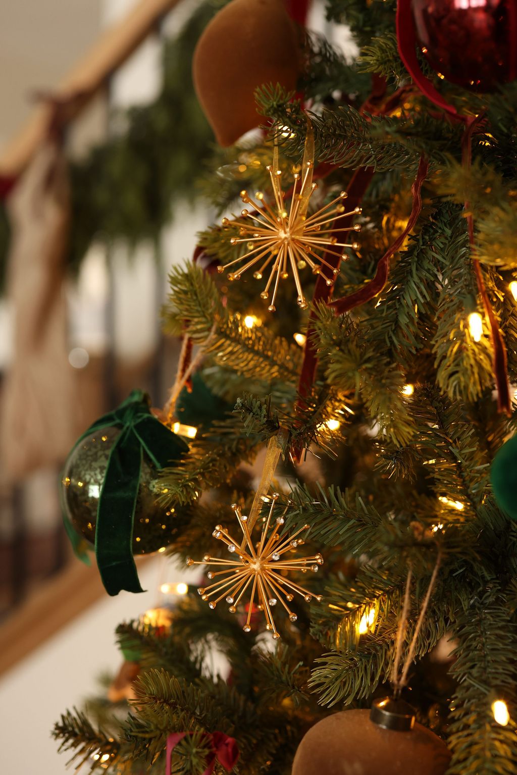 Close-up of a Christmas tree with gold starburst ornaments and red berries.