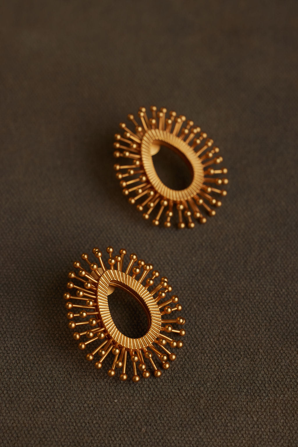 Pair of gold hoop earrings on a dark brown background