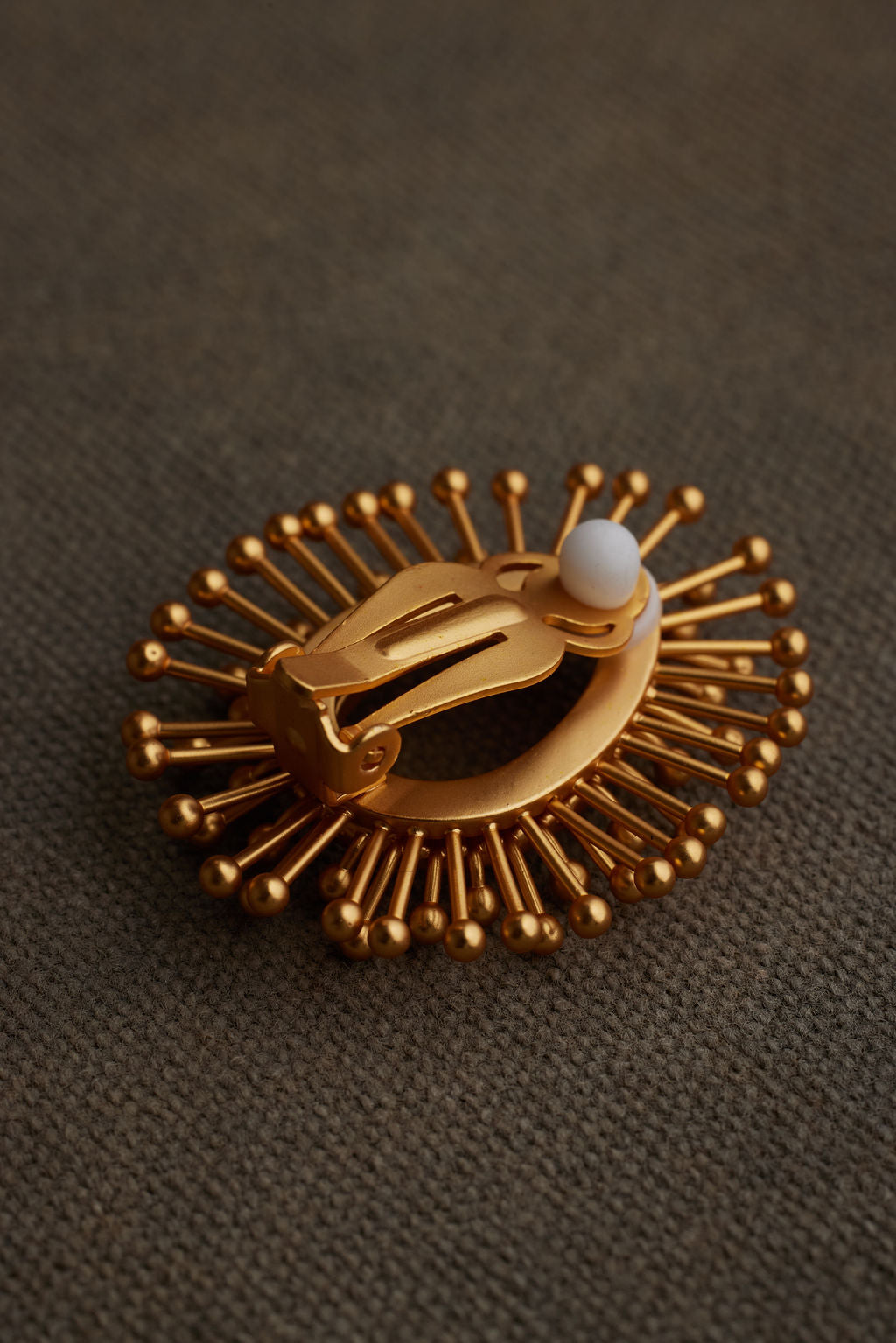 Gold brooch with a central design on a brown textured background