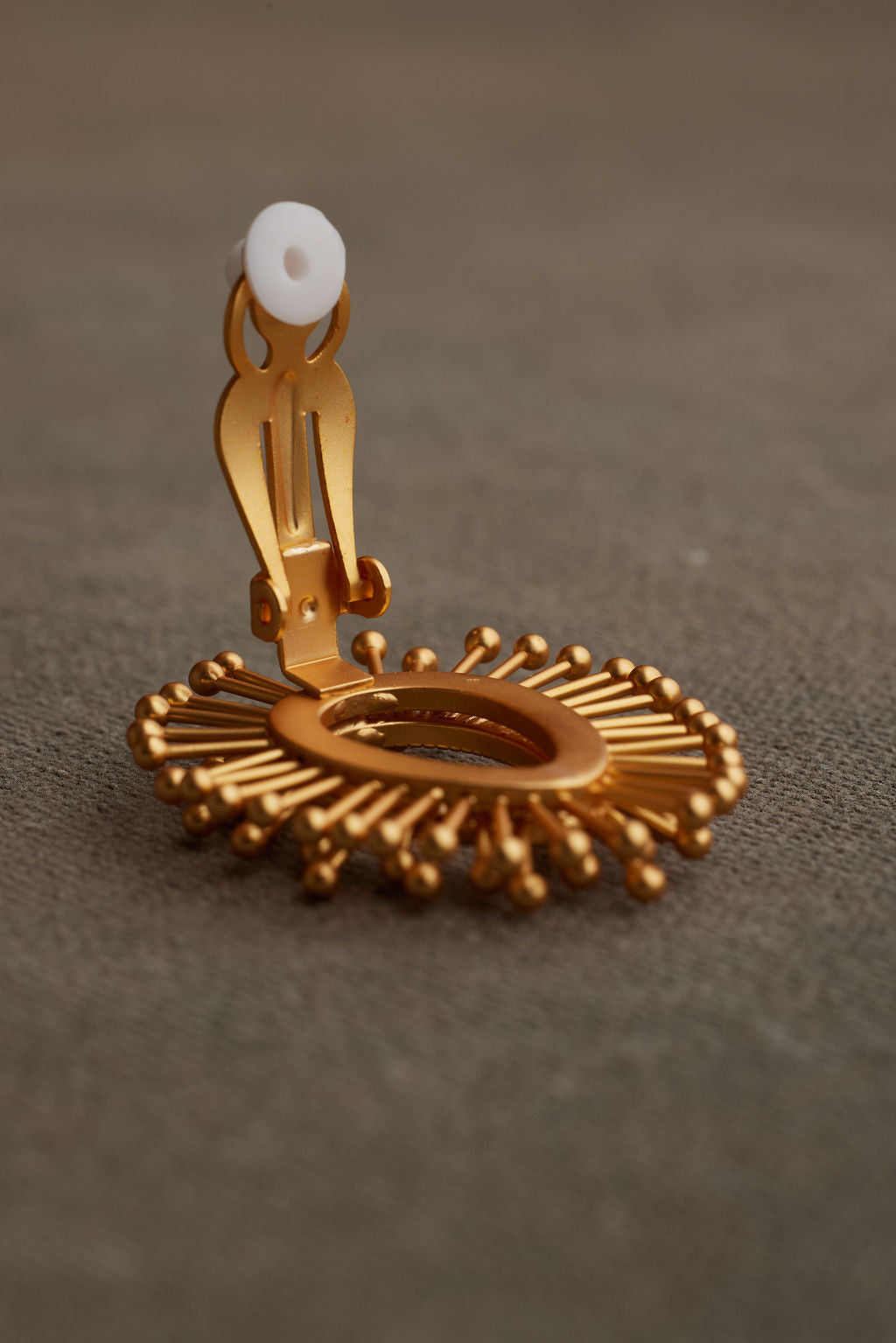Gold earring with a pearl on a brown background