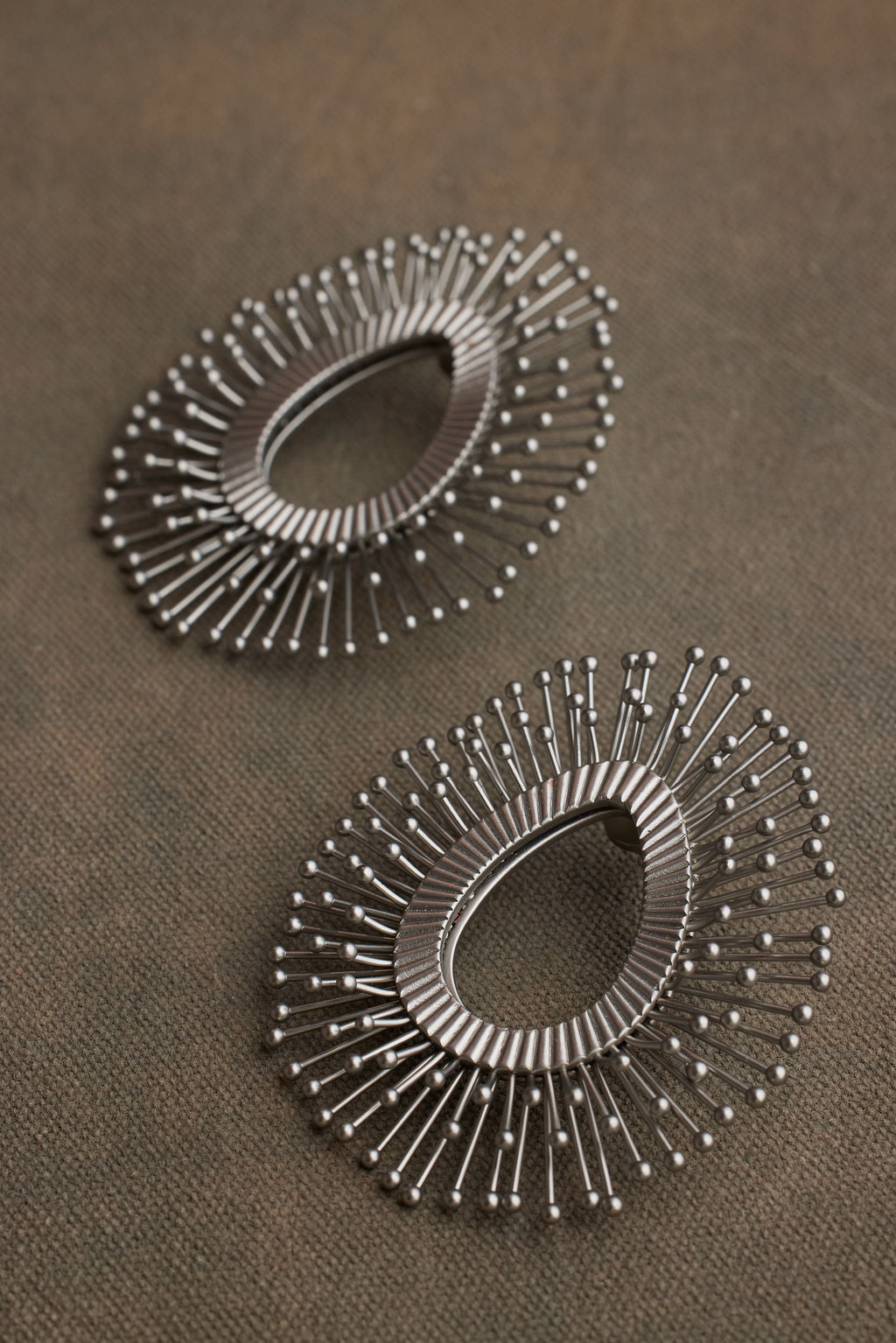 Pair of silver hoop earrings on a brown fabric background