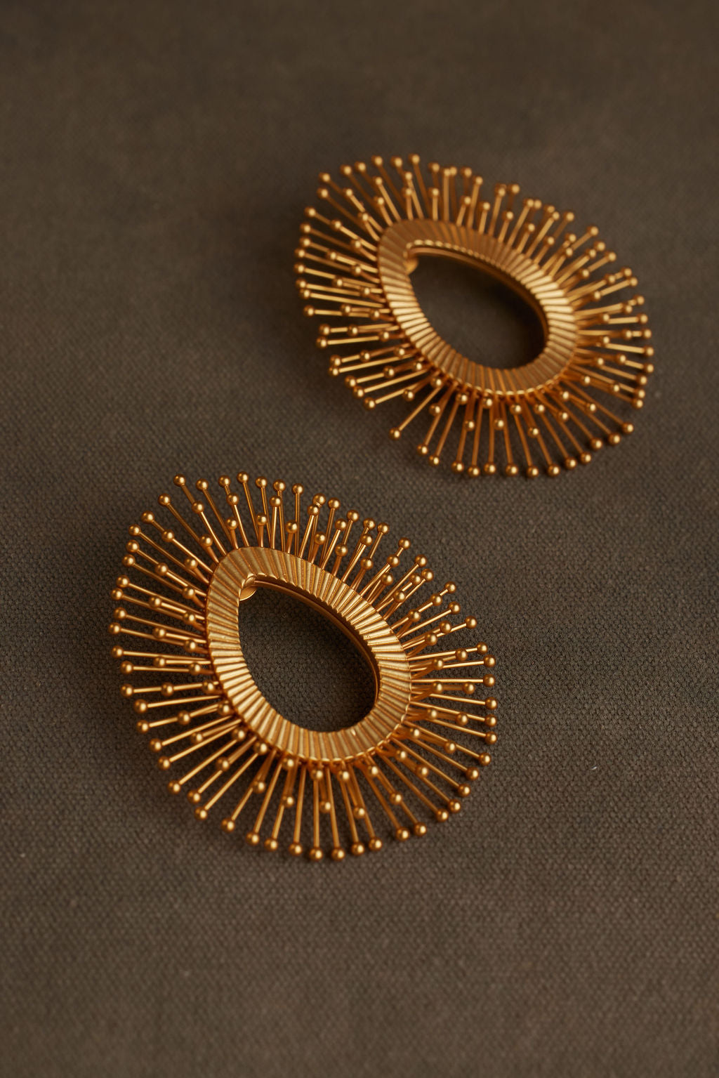 Pair of gold hoop earrings on a dark fabric background